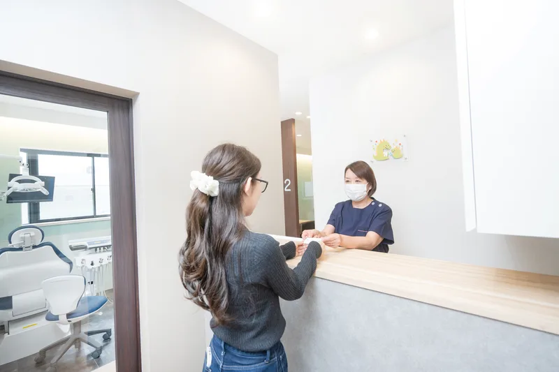 受付カウンターでスタッフから書類を受け取る来院者
