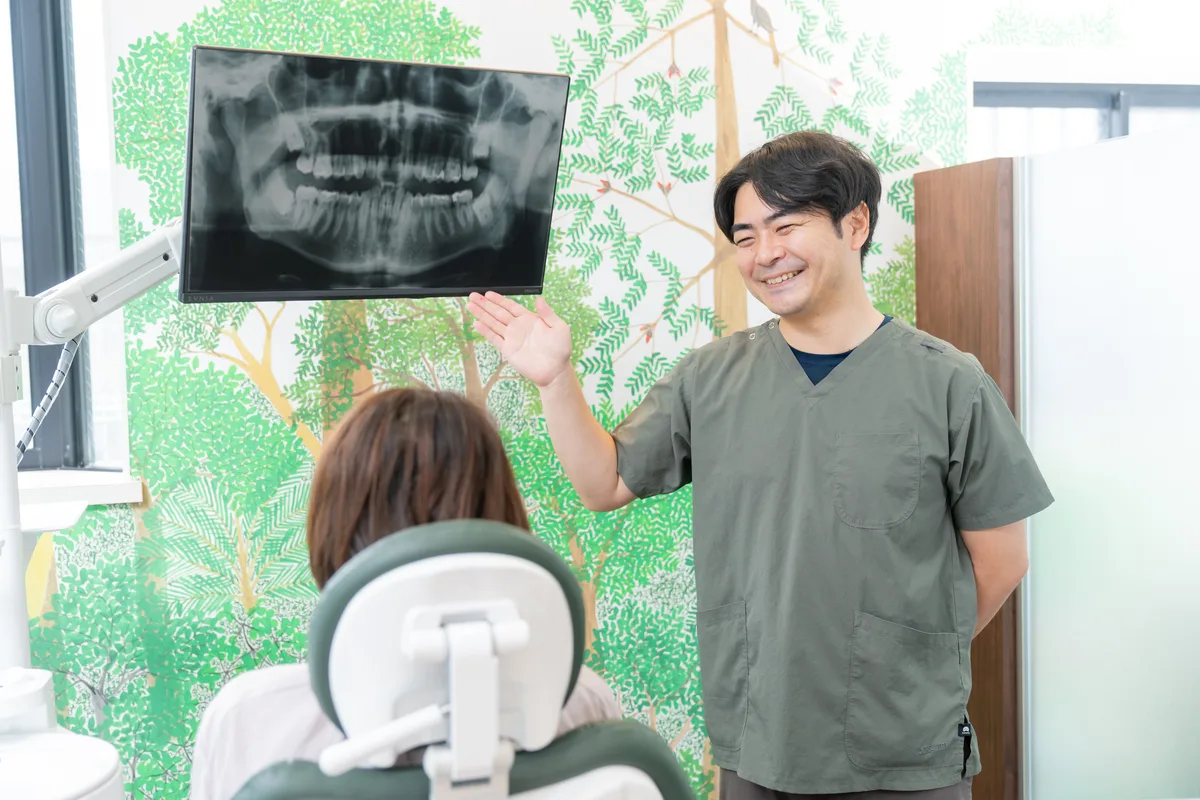 歯のレントゲン画像をモニターに映し、患者さんに説明する歯科医師