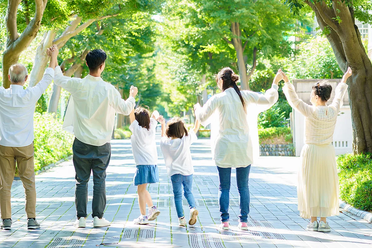 並木道で手をつないで歩く3世代の家族の後ろ姿