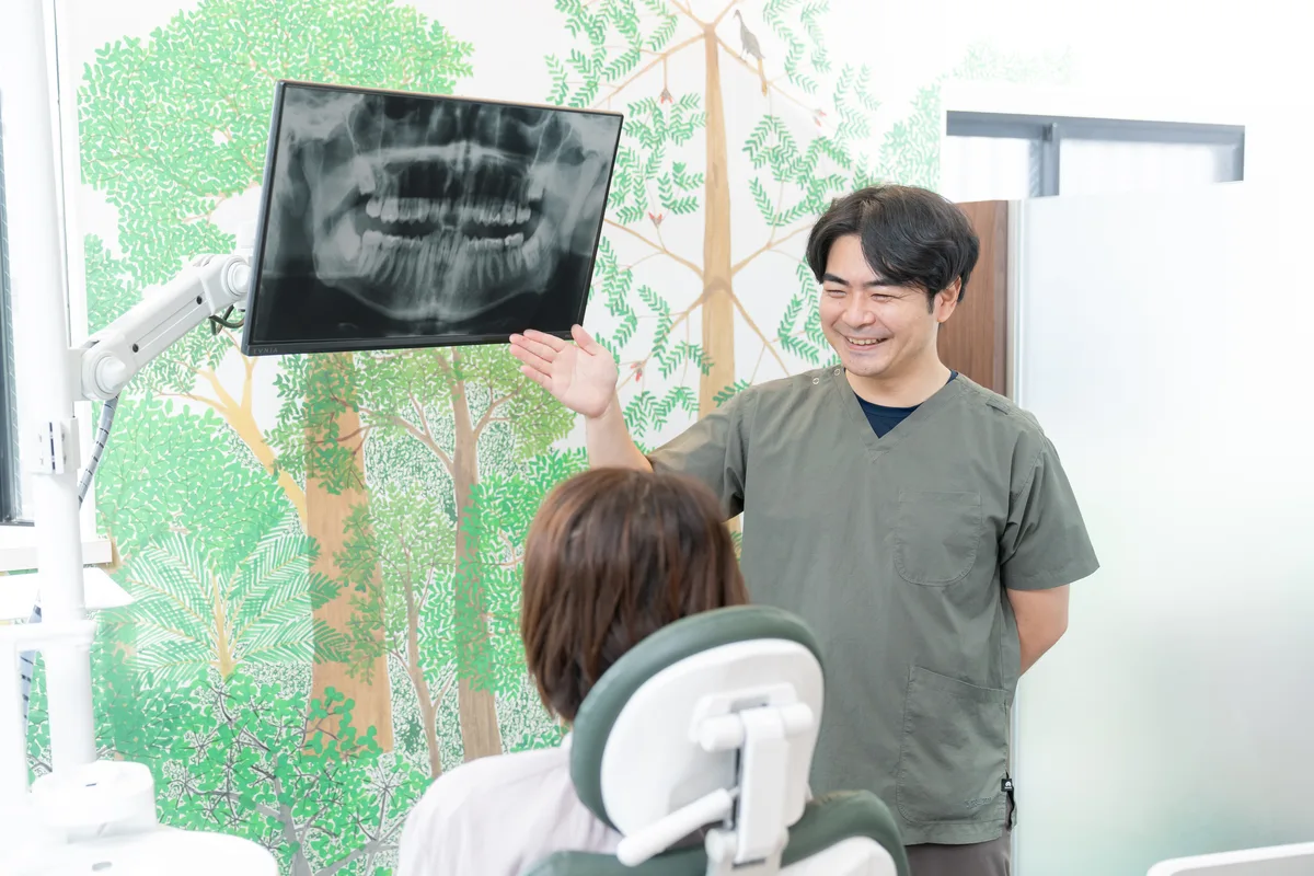 歯のレントゲン画像をモニターに映し、患者さんに説明する歯科医師